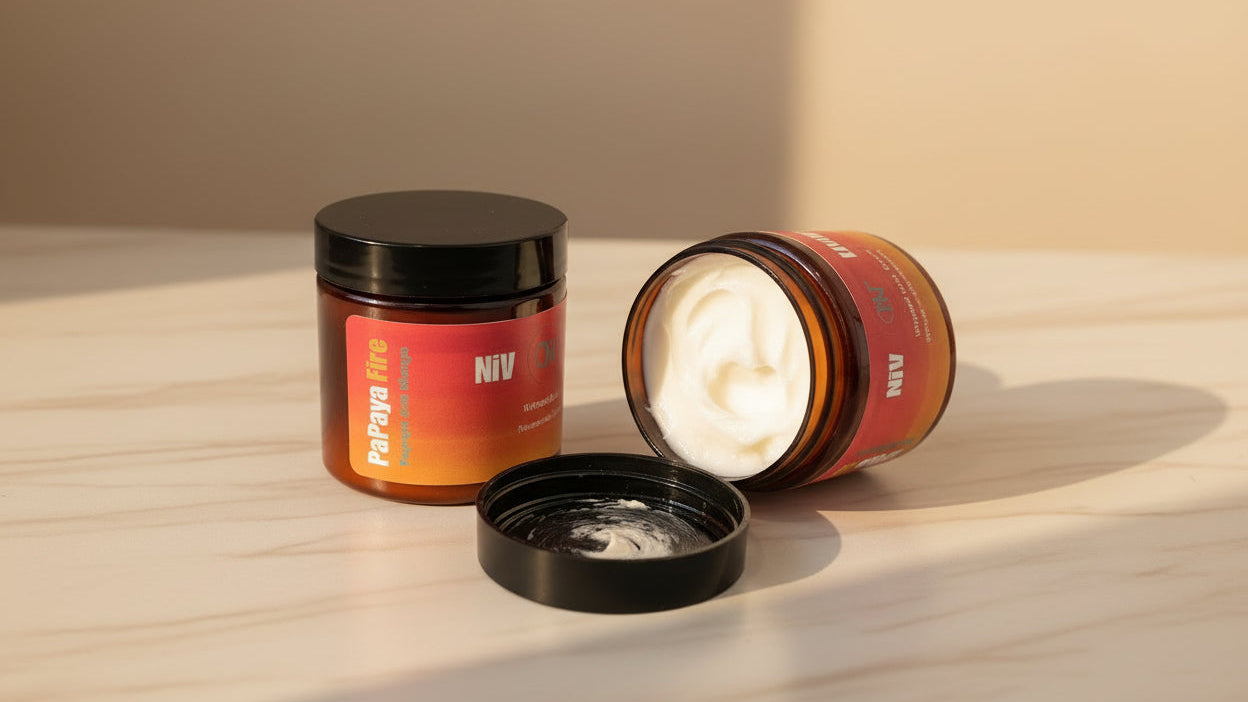 Two jars of hair product, one open showing white cream, on a wooden surface with a neutral background.